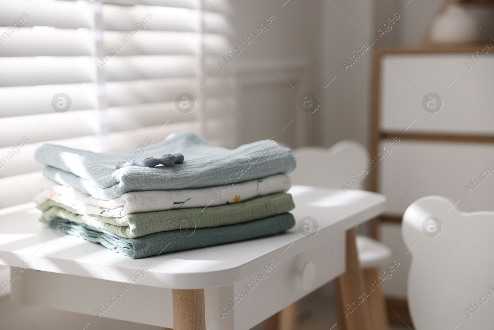 Photo of Baby swaddles and teether on table indoors. Space for text