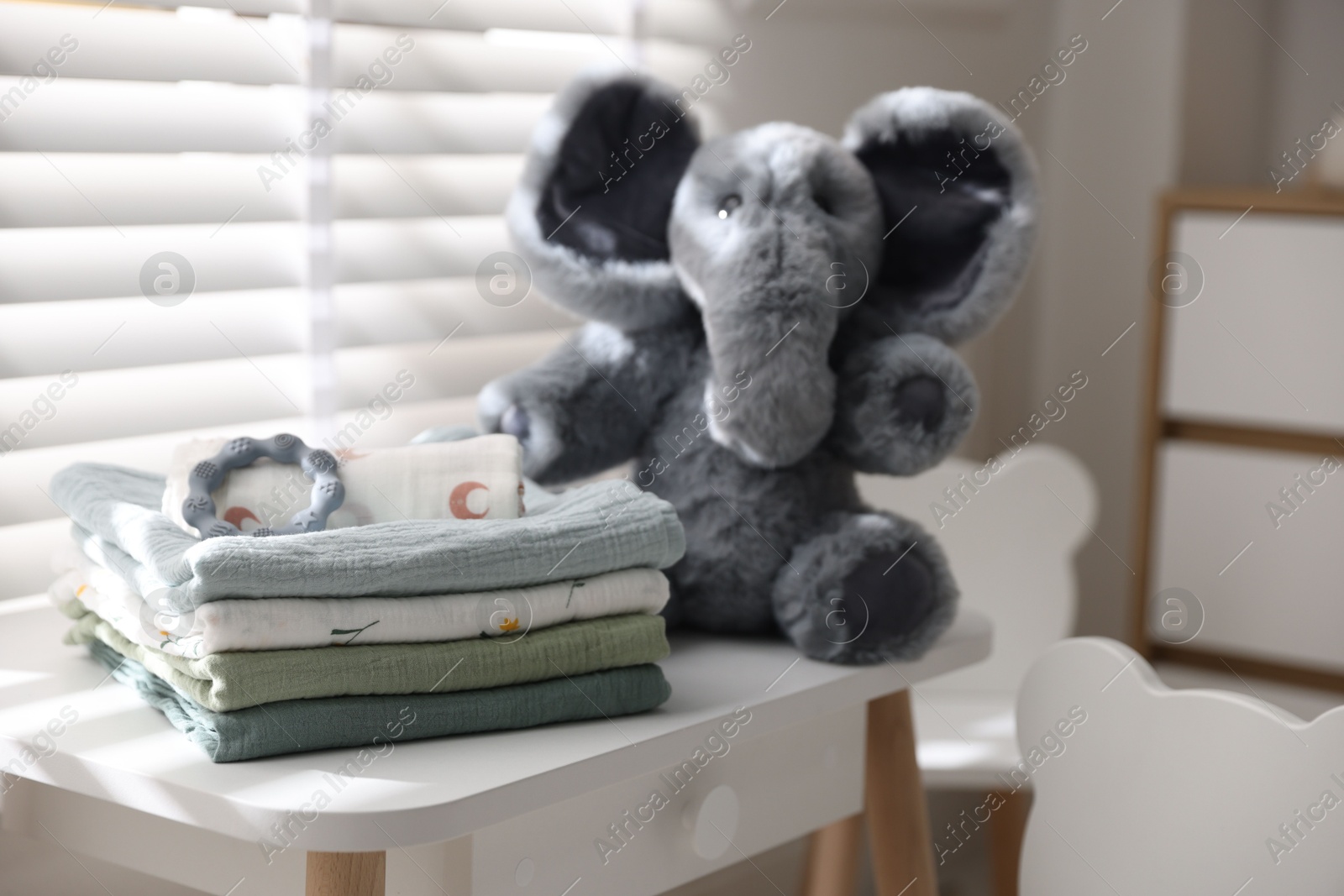 Photo of Baby swaddles, toy elephant and teether on table indoors