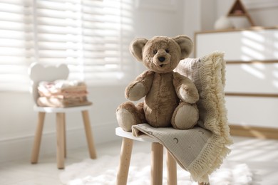 Photo of Cute teddy bear on chair in child's room. Space for text