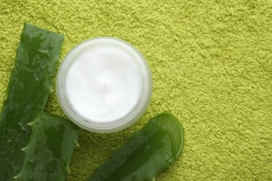 Photo of Cream and aloe leaves on green background, flat lay. Space for text