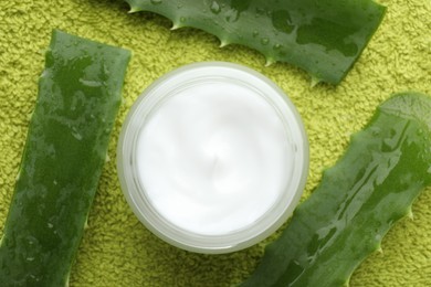 Cream and aloe leaves on green background, flat lay