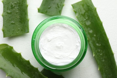 Cream and aloe leaves on white textured background, flat lay