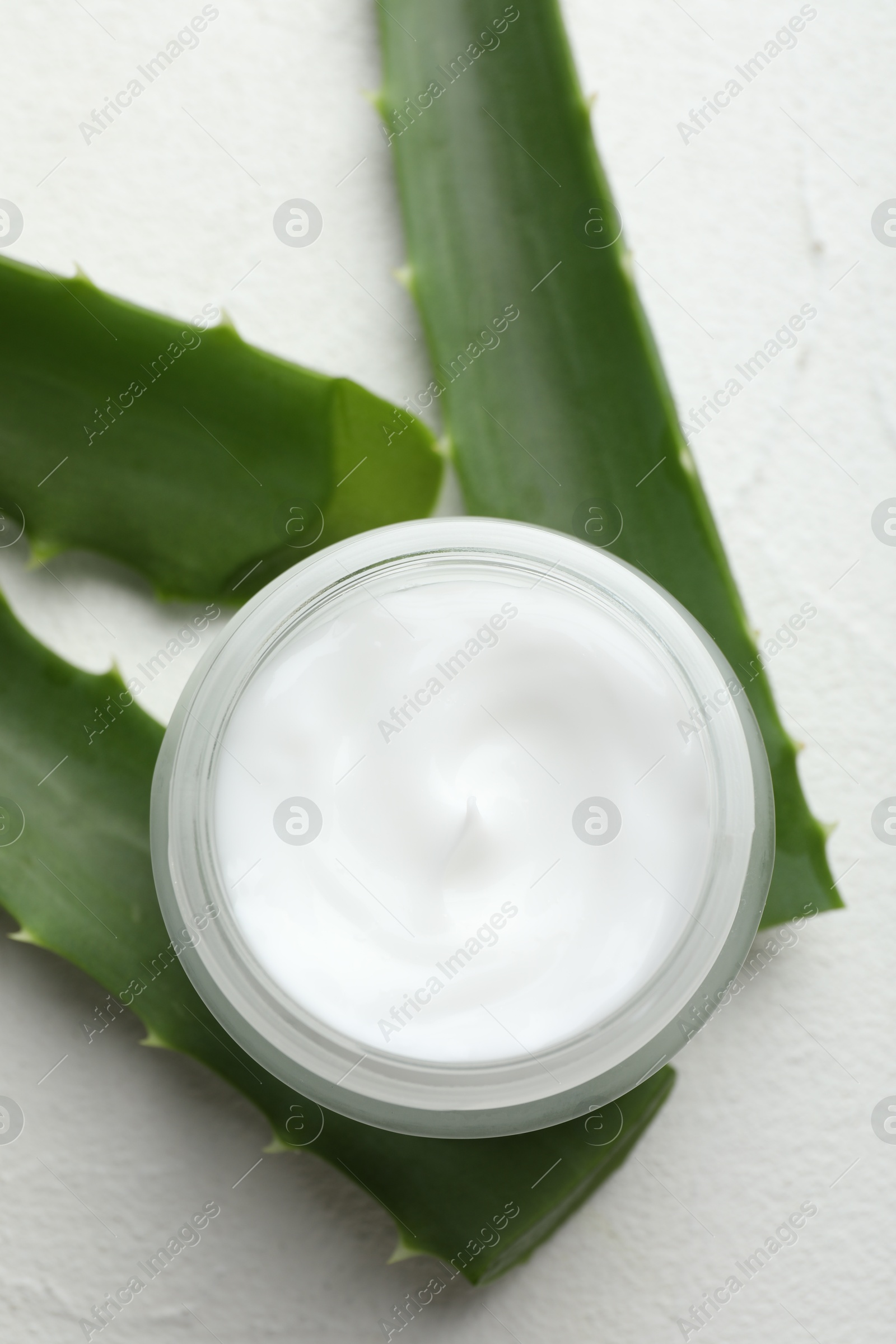 Photo of Cream and aloe leaves on white textured background, flat lay