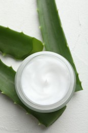 Cream and aloe leaves on white textured background, flat lay