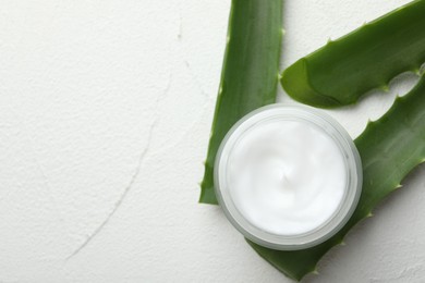 Cream and aloe leaves on white textured background, flat lay. Space for text