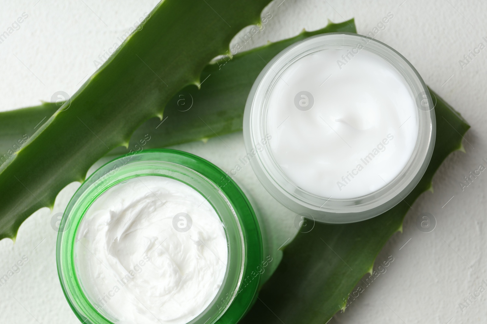 Photo of Cream and aloe leaves on white textured background, flat lay