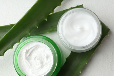 Cream and aloe leaves on white textured background, flat lay