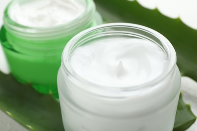 Cream and aloe leaves on white background, closeup