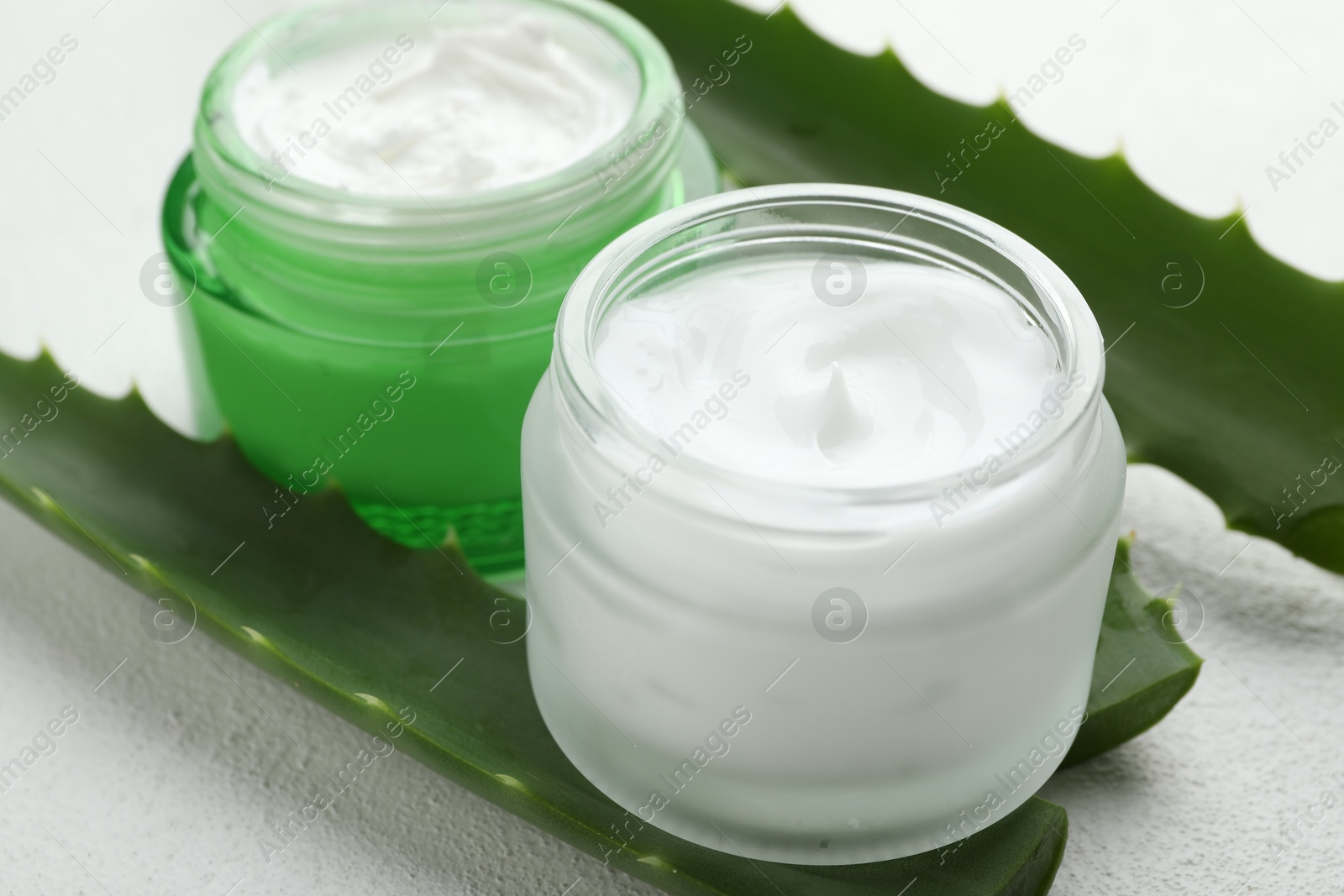 Photo of Cream and aloe leaves on white textured background