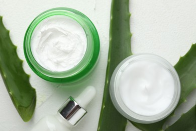 Cosmetic products and aloe leaves on white textured background, flat lay