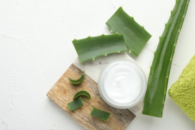 Cream and aloe leaves on white textured background, flat lay