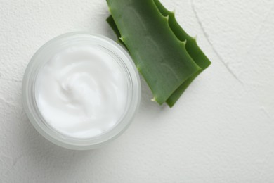 Cream and aloe leaves on white textured background, top view