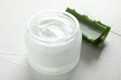 Cream and aloe leaves on white textured background, closeup