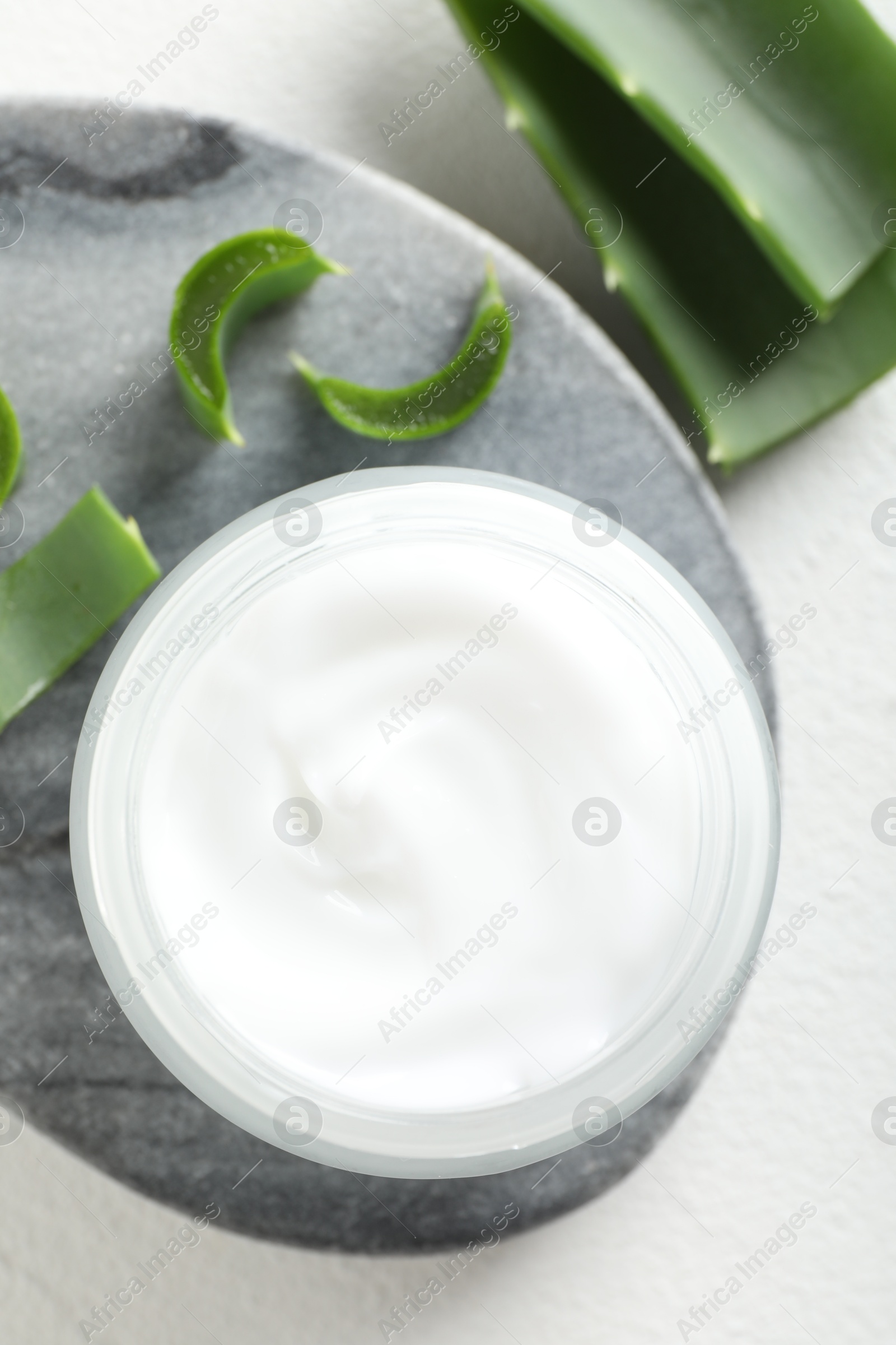 Photo of Cream and aloe leaves on white background, flat lay