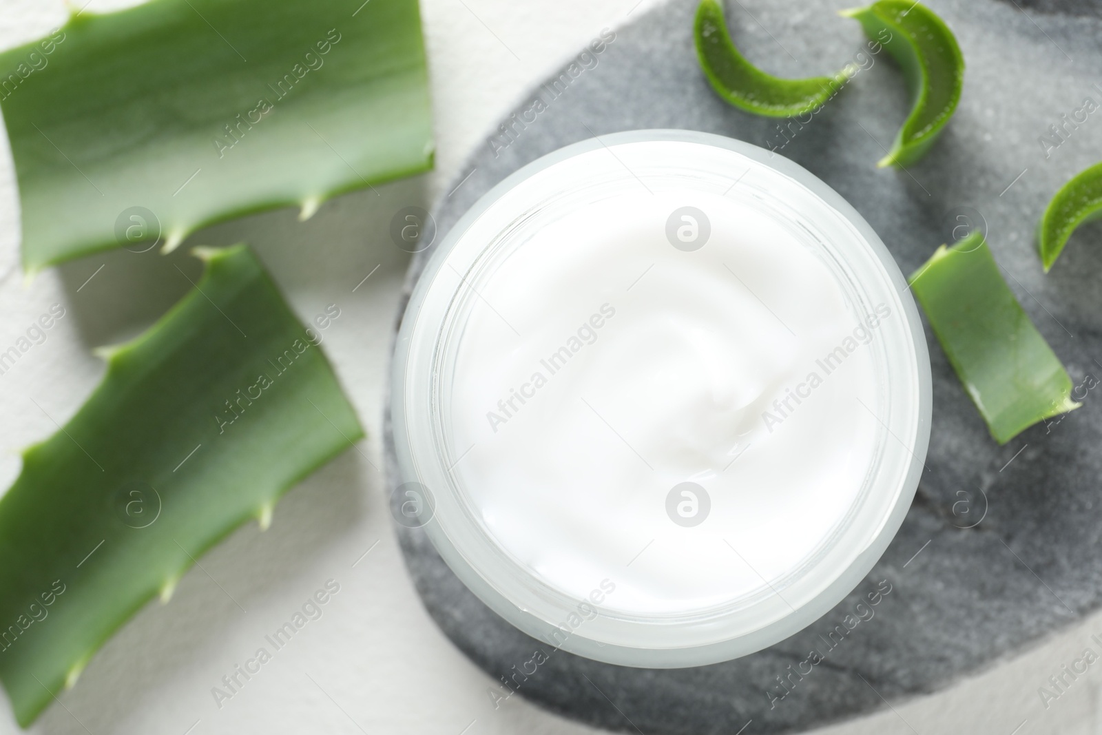 Photo of Cream and aloe leaves on white background, flat lay