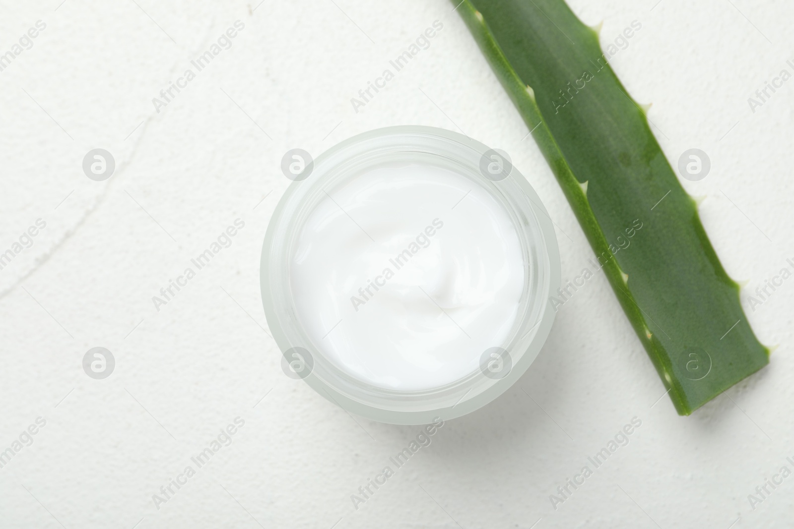 Photo of Cream and aloe leaves on white textured background, top view. Space for text