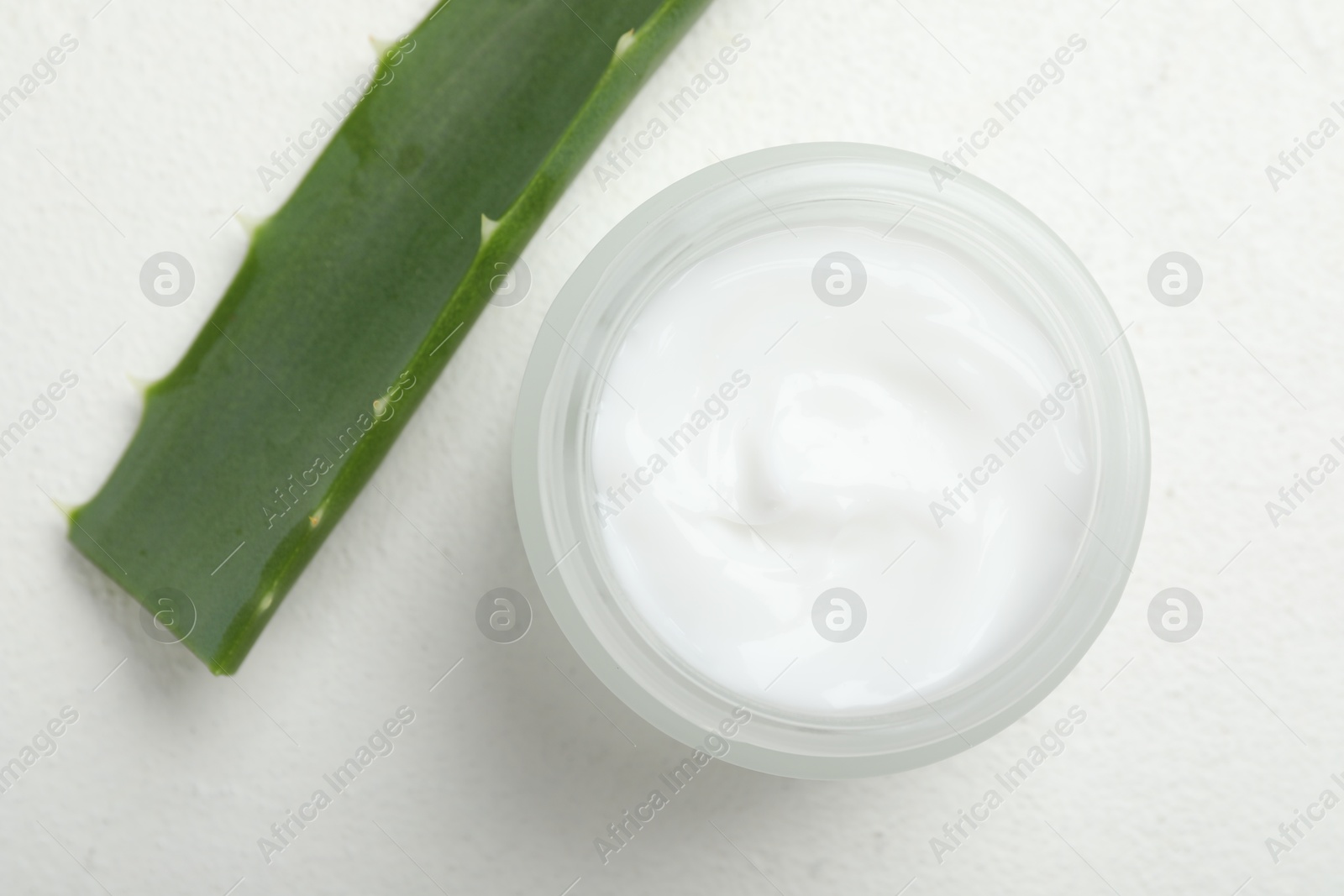 Photo of Cream and aloe leaves on white textured background, top view