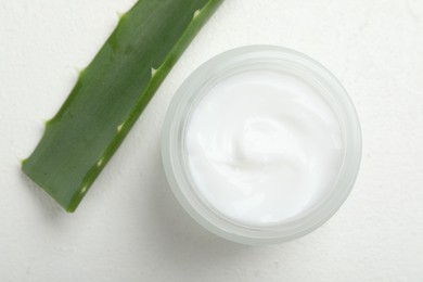 Cream and aloe leaves on white textured background, top view