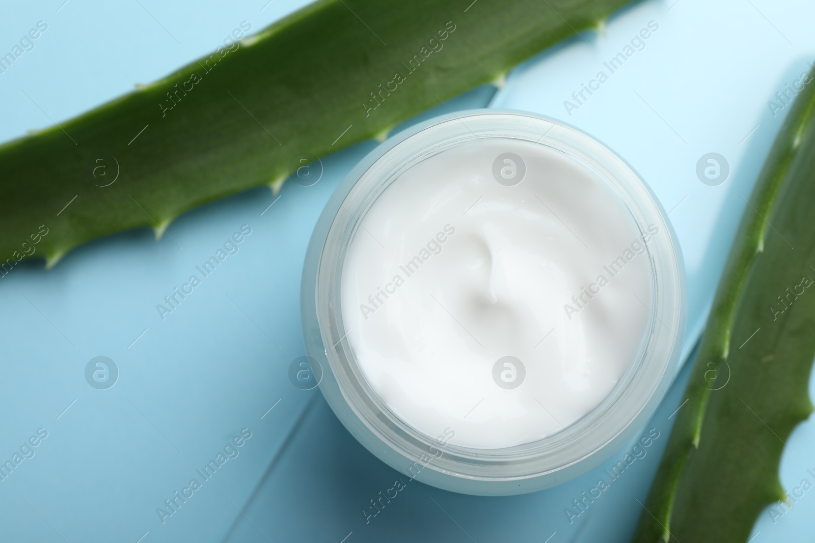 Photo of Cream and aloe leaves on light blue background