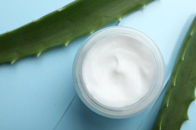 Photo of Cream and aloe leaves on light blue background