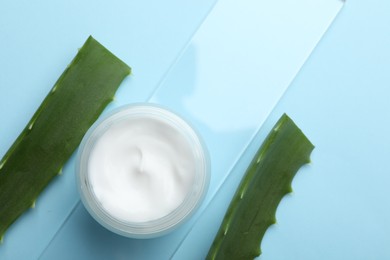 Cream and aloe leaves on light blue background, flat lay. Space for text