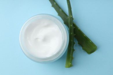 Cream and aloe leaves on light blue background, flat lay