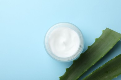 Cream and aloe leaves on light blue background, flat lay. Space for text