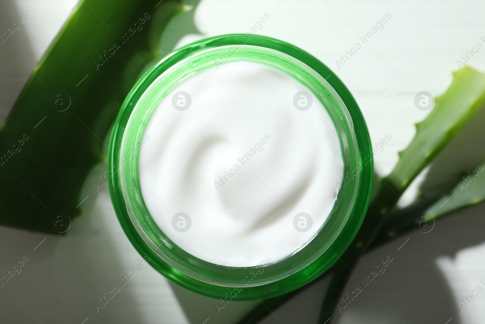 Photo of Cream and aloe leaves on white wooden background, flat lay