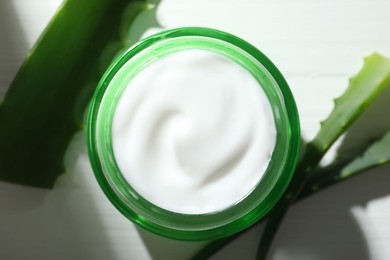 Photo of Cream and aloe leaves on white wooden background, flat lay