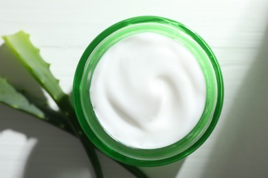 Photo of Cream and aloe leaves on white wooden background, flat lay