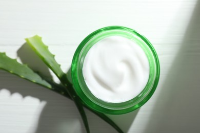 Cream and aloe leaves on white wooden background, flat lay