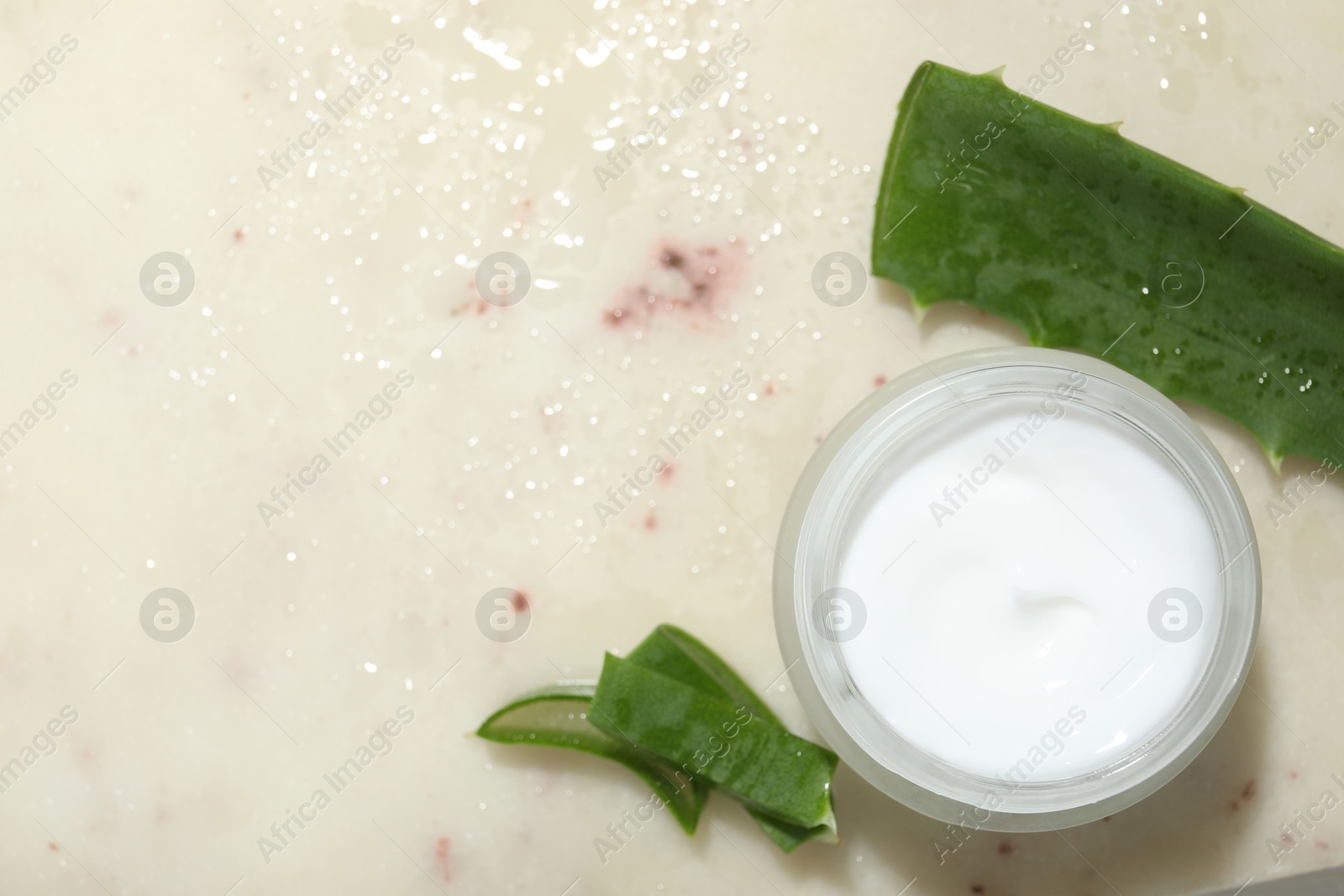 Photo of Cream and aloe leaves on light background, flat lay. Space for text