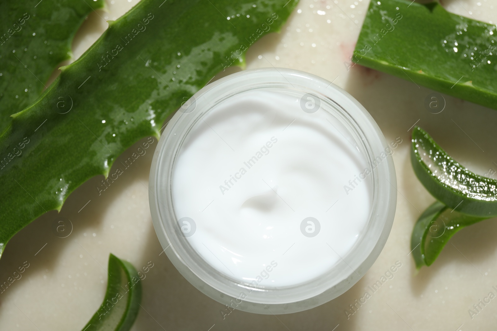 Photo of Cream and aloe leaves on light background, flat lay