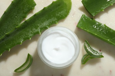 Photo of Cream and aloe leaves on light background, flat lay