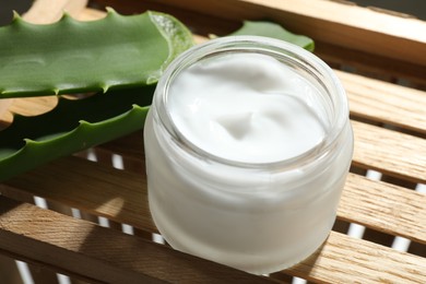 Cream and aloe leaves on wooden background, closeup