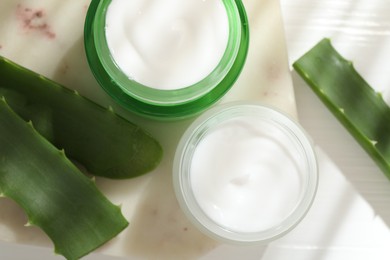 Photo of Cream and aloe leaves on light background, flat lay