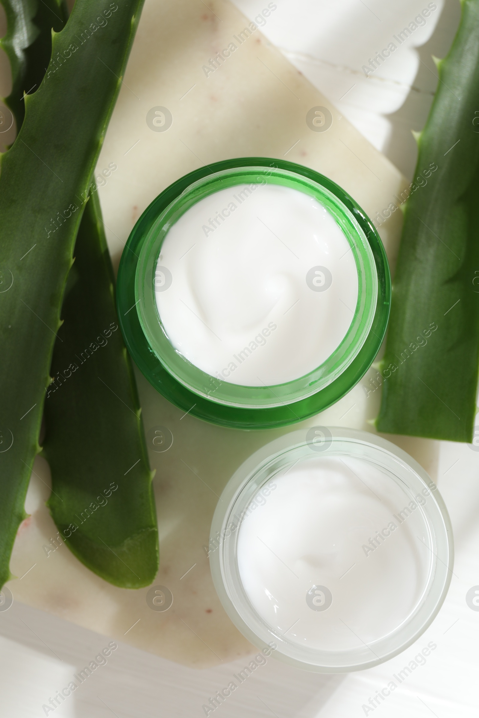 Photo of Cream and aloe leaves on light background, flat lay