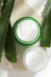 Photo of Cream and aloe leaves on light background, flat lay