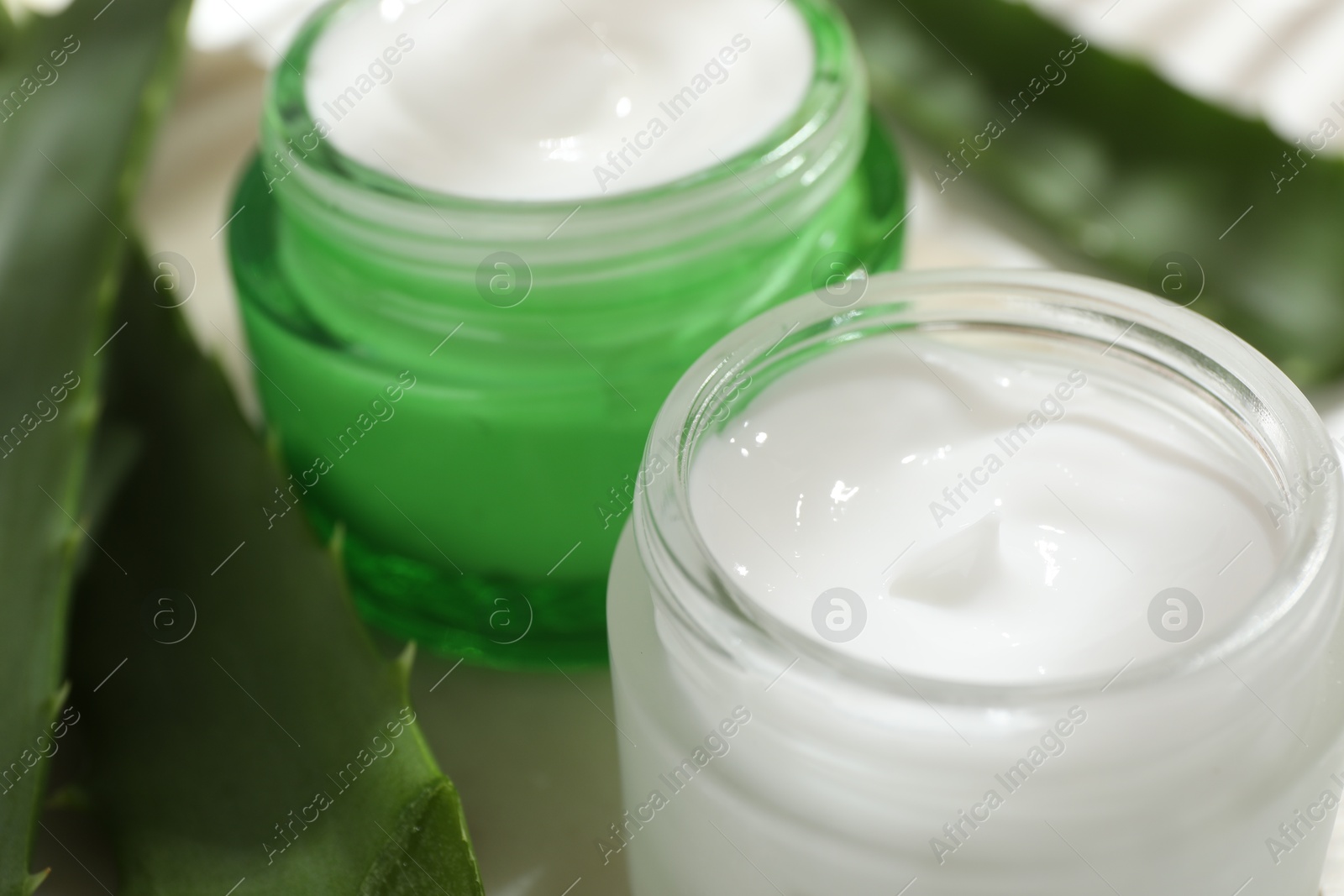 Photo of Cream and aloe leaves on light background, closeup