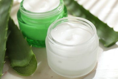 Photo of Cream and aloe leaves on light background, closeup