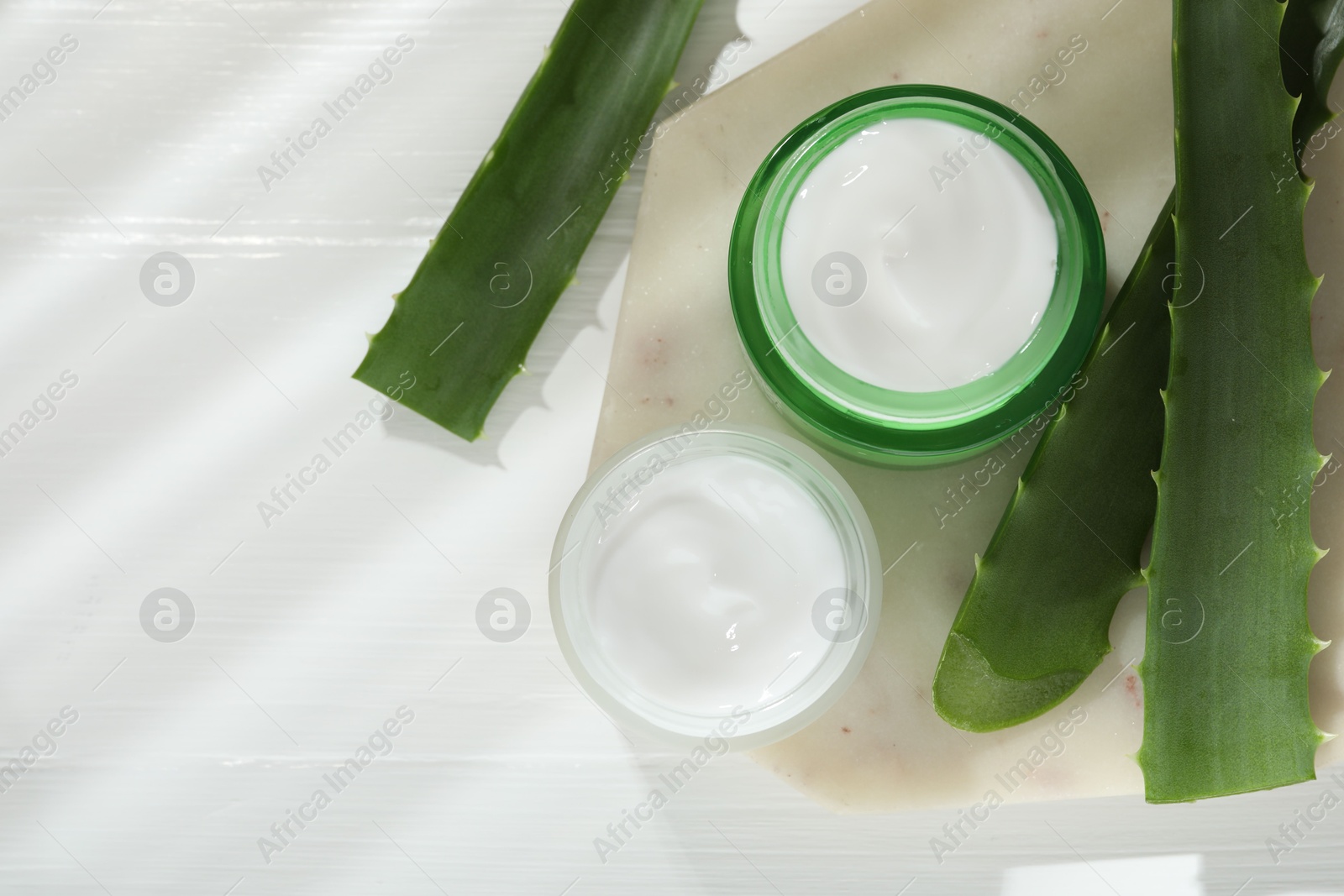 Photo of Cream and aloe leaves on white wooden background, flat lay. Space for text