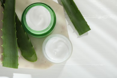 Cream and aloe leaves on white wooden background, flat lay