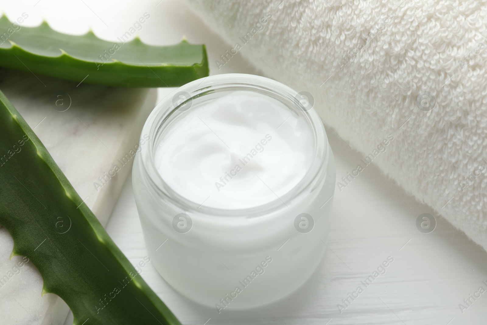 Photo of Cream and aloe leaves on white wooden background, closeup