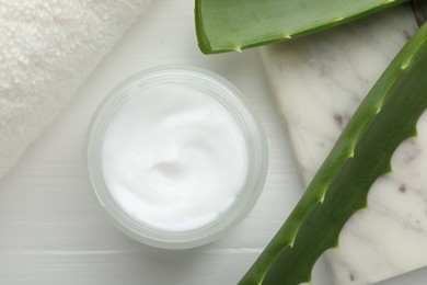 Cream and aloe leaves on white wooden background, flat lay