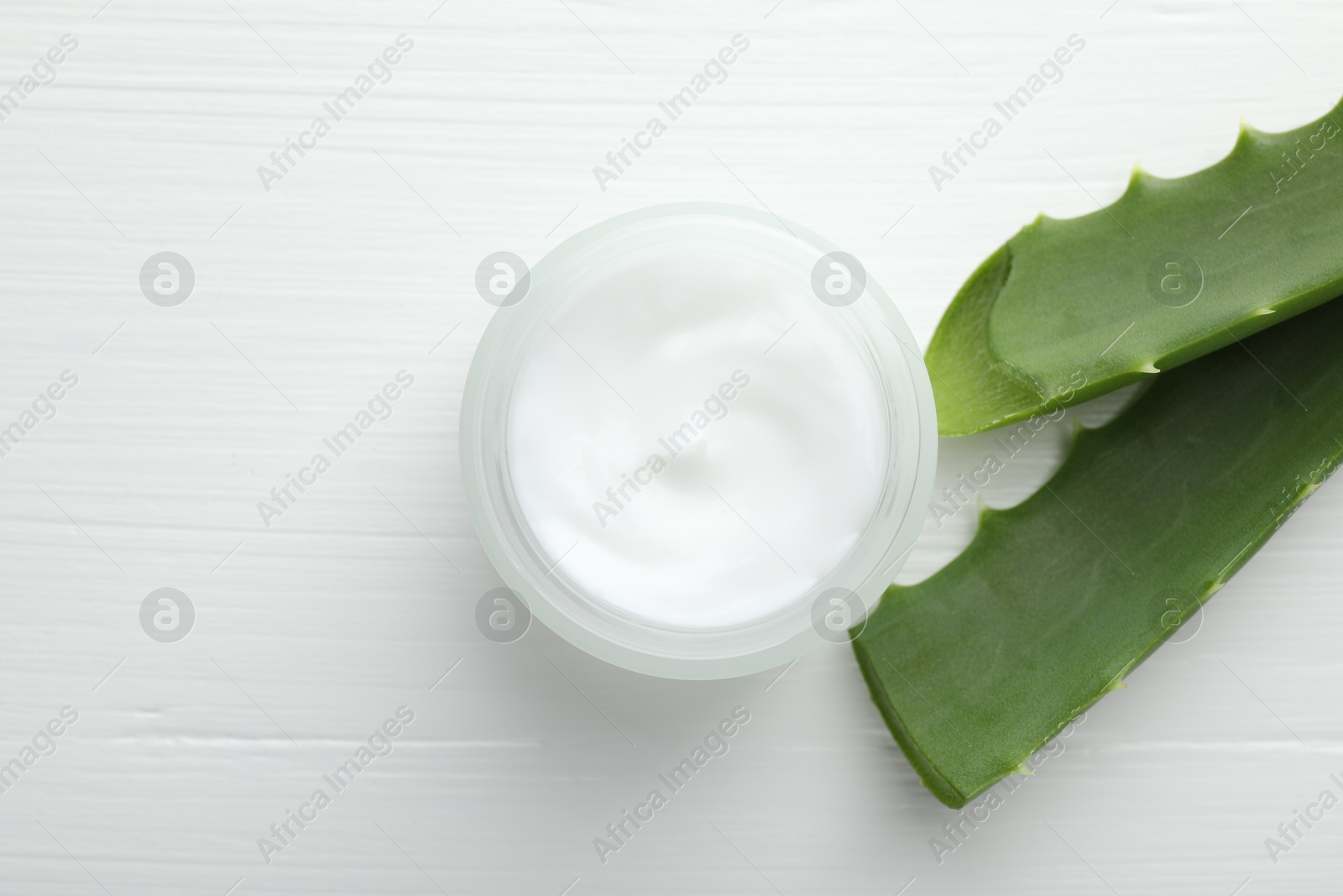 Photo of Cream and aloe leaves on white wooden background, flat lay