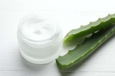 Cream and aloe leaves on white wooden background, closeup