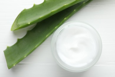 Cream and aloe leaves on white wooden background, flat lay