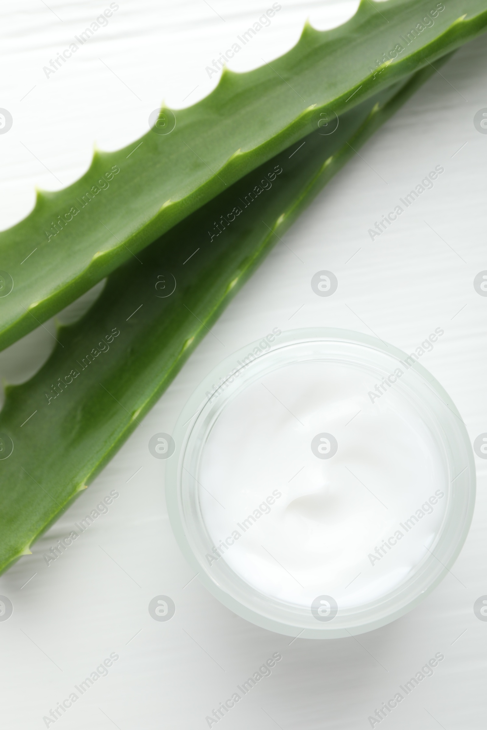 Photo of Cream and aloe leaves on white wooden background, flat lay