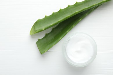 Cream and aloe leaves on white wooden background, flat lay