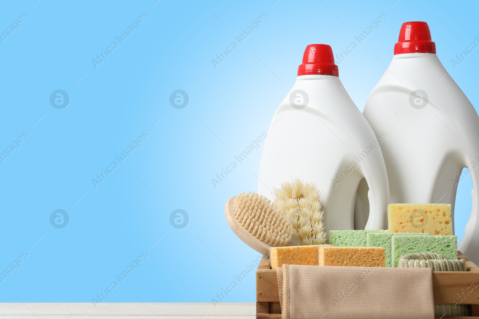 Image of Eco-friendly cleaning products on table against light blue gradient background, space for text